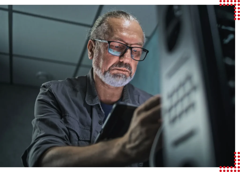 Ein älterer Mann der konzentriert und mit modernster Ausrüstung in einem Serverraum arbeitet