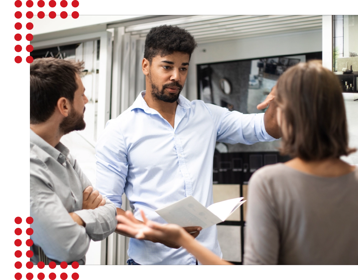 Drei Personen unterhalten sich konzentriert zusammen in einem sauberen und ordentlichen Verkaufsraum