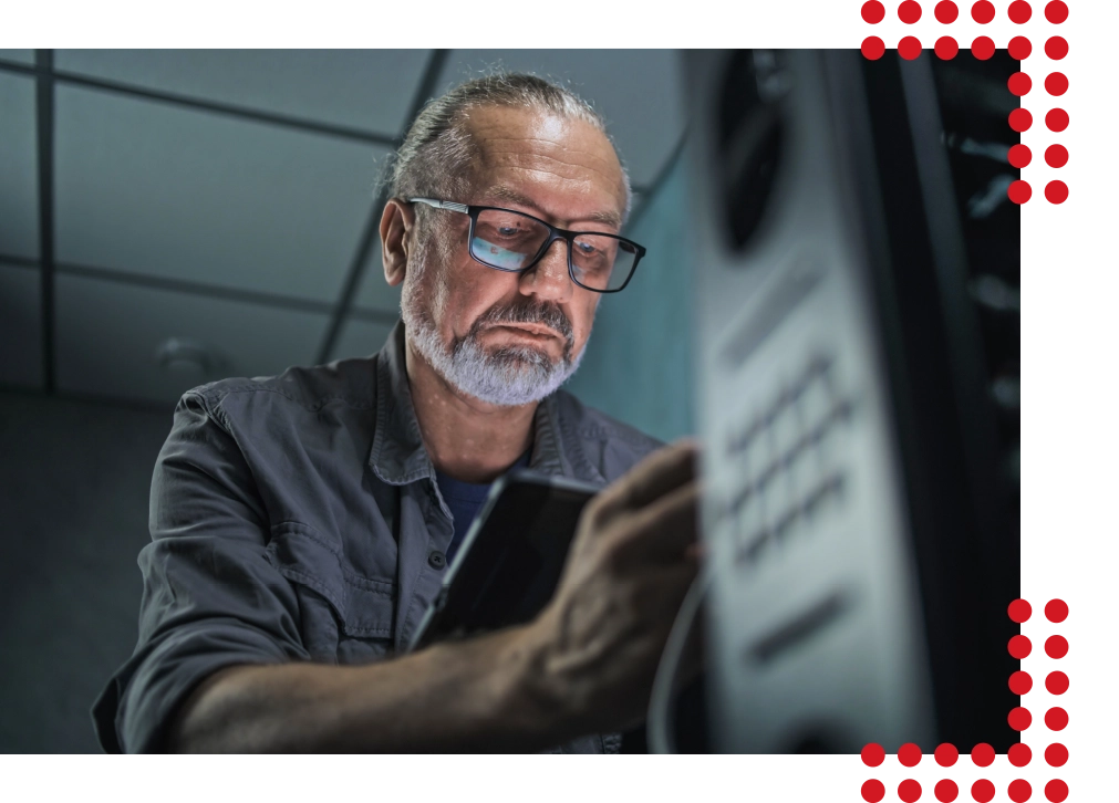 Ein älterer Mann der konzentriert und mit modernster Ausrüstung in einem Serverraum arbeitet