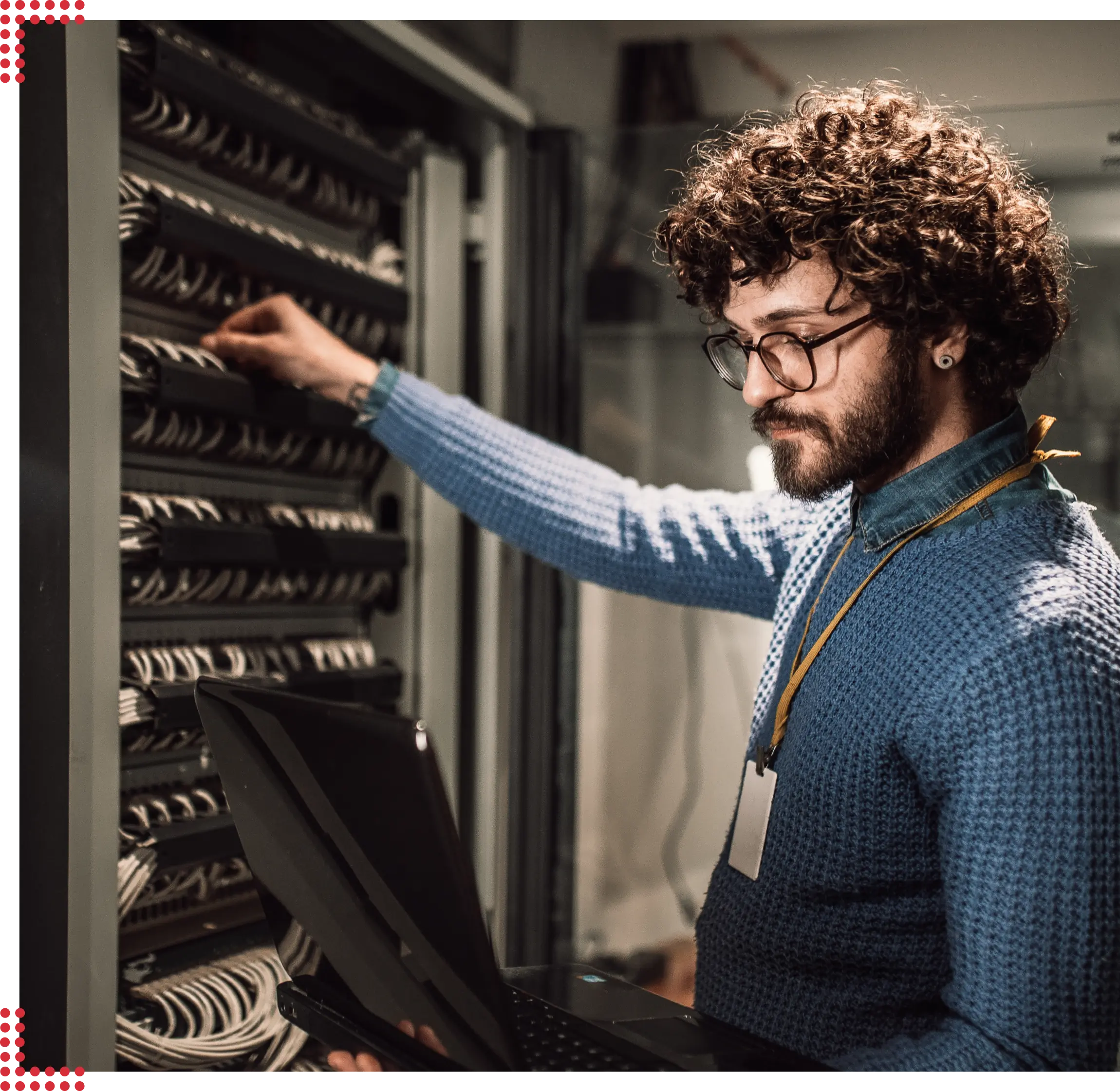 Ein junger sympathischer Mann mit wilden Locken und einem leichten Lächeln steht in einem Serverraum und richtet sorgfältig alles ein