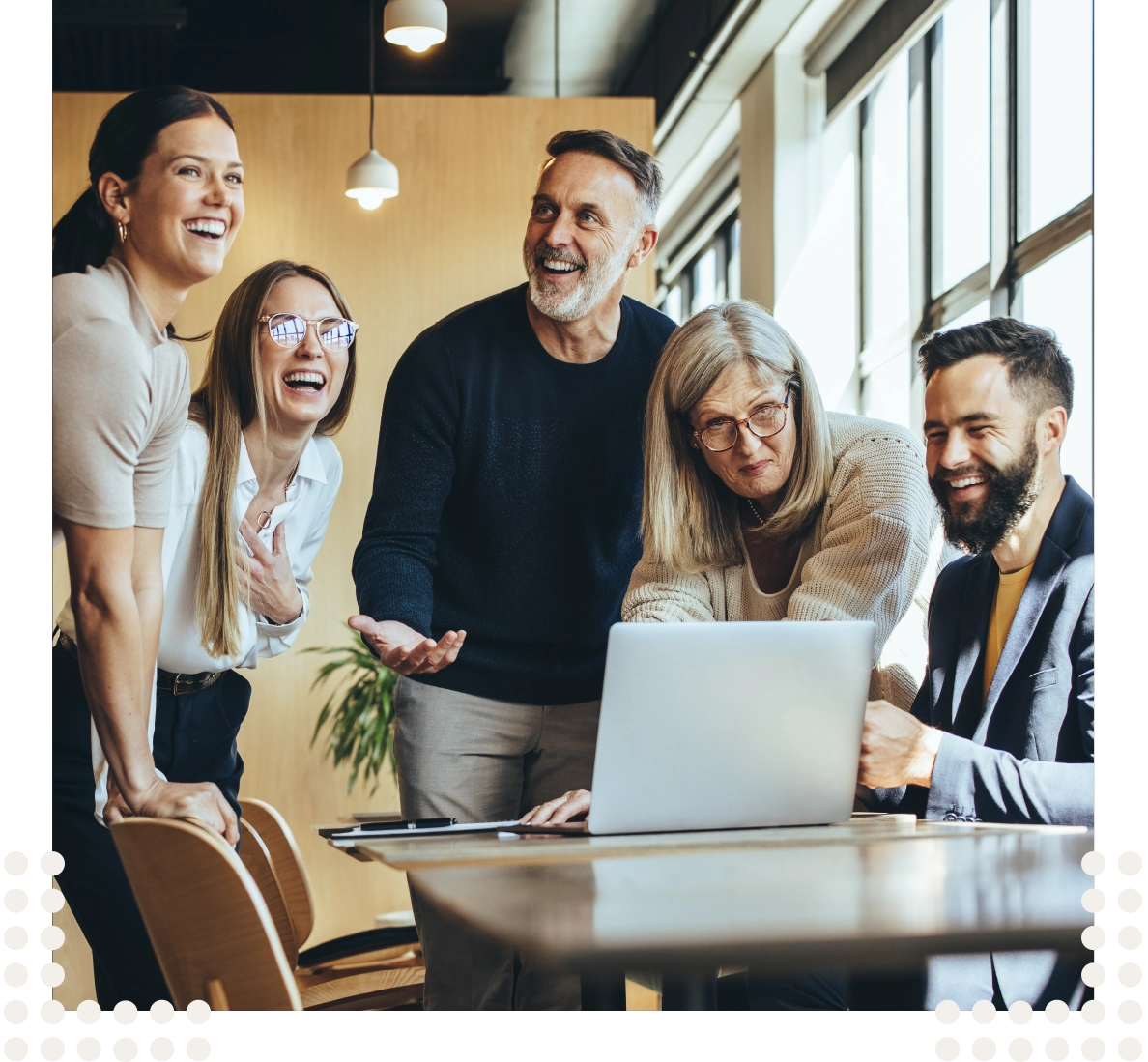 Eine toll gemischte Gruppe an Menschen sitzen um einen Laptop und arbeiten gemeinsam in einem modernen Arbeitsumfeld